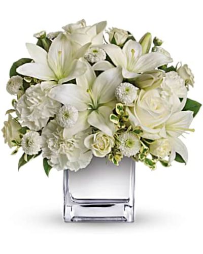 <p>The arrangement features a stunning mix of white roses, spray roses, Asiatic lilies, carnations, and button spray chrysanthemums. Accented with fresh greenery and presented in a mirrored silver cube vase, the bouquet offers a modern, luminous touch that enhances its clean and peaceful aesthetic.</p>