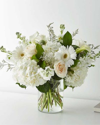 <p>This premium bouquet features white roses, hydrangeas, gerbera daisies, mini calla lilies, and delicate limonium. Each flower is chosen for its purity, texture, and classic appeal, then carefully arranged in a clear glass vase to let the natural beauty shine.</p>