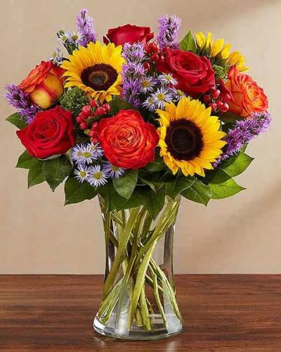 <p>This bouquet overflows with rich orange roses, golden sunflowers, bronze daisies, deep red carnations, and golden solidago. Fresh greenery adds contrast and fullness, while the arrangement is presented in a country-inspired vase or basket that enhances its natural, down-to-earth appeal.</p>