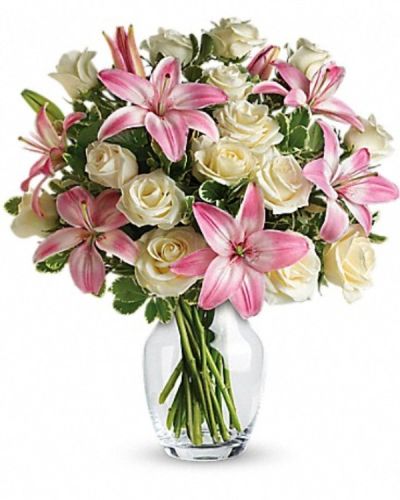 <p>An eye-catching display of roses and lilies is perfectly arranged in a feminine vase which makes a beautiful and lasting impression. Elegant white roses and sweet pink asiatic lilies are hand-arranged with greens.</p>