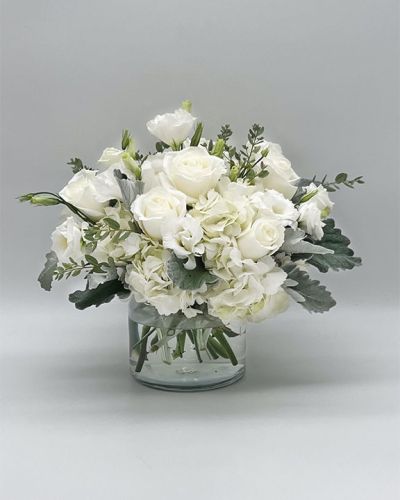 <p>This bouquet features a radiant mix of fresh white blooms such as roses, lilies, hydrangeas, and spray chrysanthemums, each carefully selected for their beauty and serene presence. Accented with soft greenery and arranged in a classic glass vase, the composition presents a clean, polished look that feels both modern and timeless.</p>