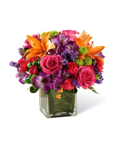 <p>This bouquet includes a bold mix of hot pink roses, orange Asiatic lilies, purple Peruvian lilies, hot pink mini carnations, green button poms, and purple statice. Lush greens and curling party ribbons add a festive flair, while the clear glass cube vase—lined with a ti leaf wrap—offers a stylish and modern presentation.</p>