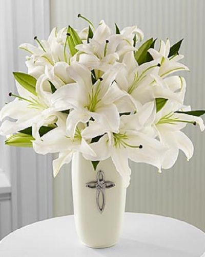 <p>Featuring radiant white lilies, this bouquet is arranged in a white ceramic vase and accented with a decorative cross, adding a spiritual touch to its graceful presence. This arrangement is a fitting choice for religious celebrations, confirmations, sympathy tributes, weddings, or special anniversaries.</p>